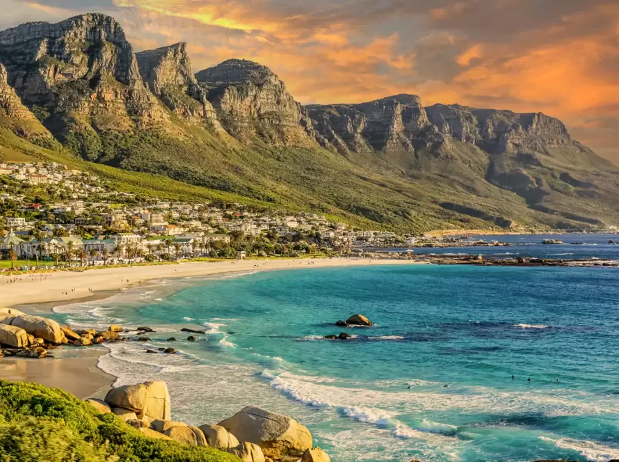 Camps Bay Beach in Cape Town, South Africa, with the iconic Twelve Apostles mountain range at sunset.