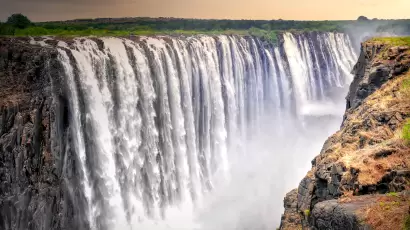 Majestic view of Victoria Falls, also called "The Smoke That Thunders," on the Zimbabwe-Zambia border, with powerful cascades plunging into misty depths of the Zambezi Gorge.