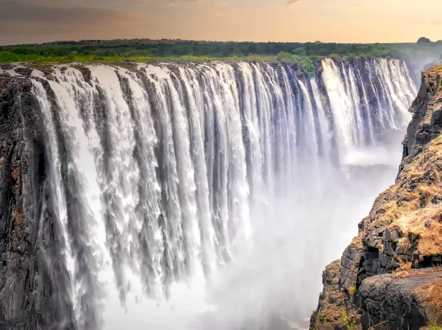 Majestic view of Victoria Falls, also called "The Smoke That Thunders," on the Zimbabwe-Zambia border, with powerful cascades plunging into misty depths of the Zambezi Gorge.