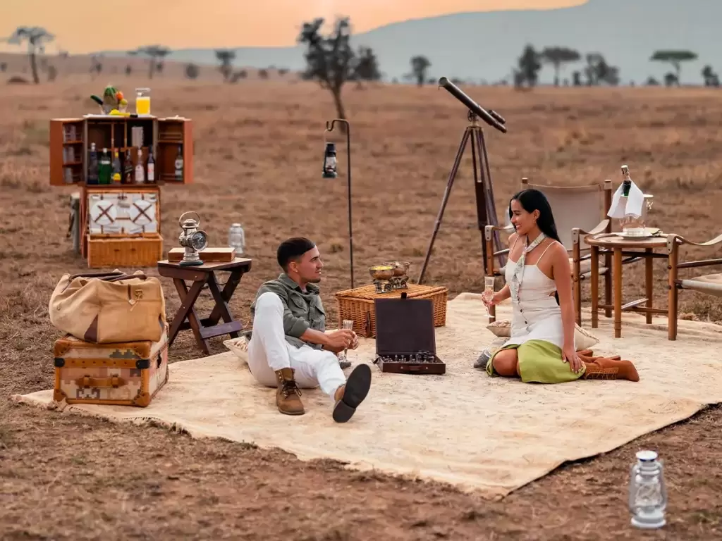 Honeymoon couple enjoying a private safari sundowner in the wild.