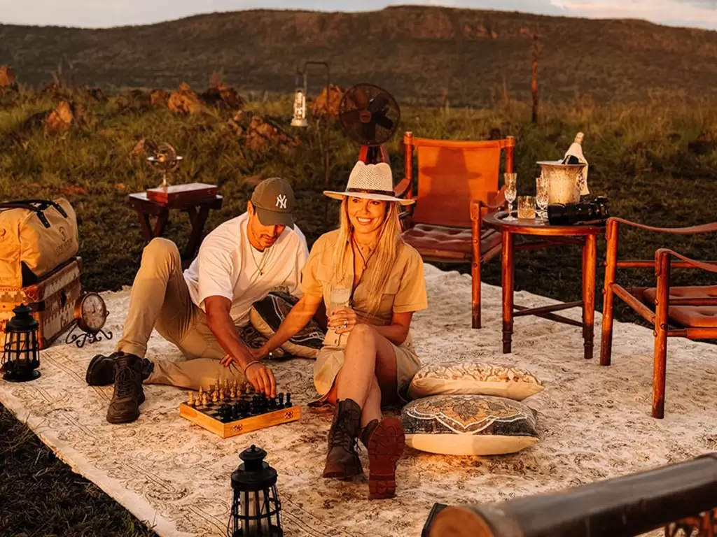 A couple enjoying a romantic sundowner picnic on a luxury African honeymoon. 