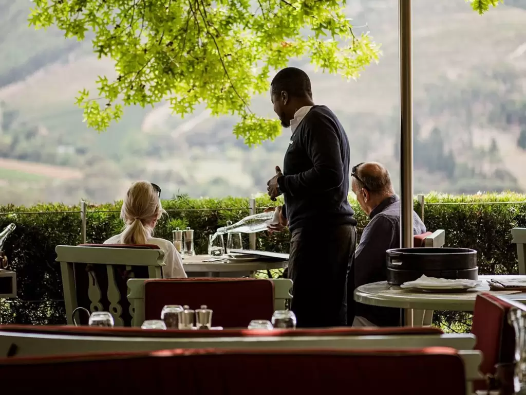 A couple experiencing wine tasting in Franschhoek, South Africa, with panoramic vineyard views.