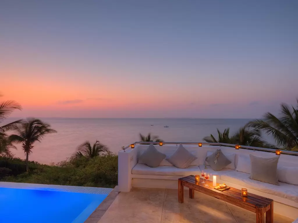 A serene sunset in Mozambique sky seen from a luxury lantern-lit patio with swimming pool at a beach resort at Vilanculos.